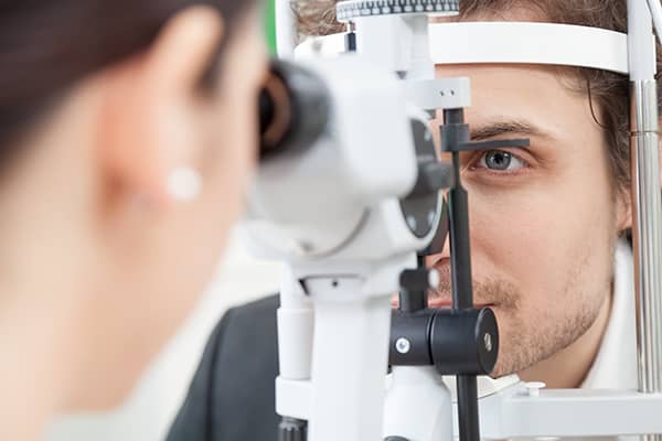 Optometrist examining young man's eyes during dry eye consultation 