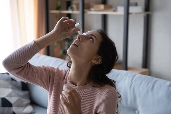 Woman applying eye drops to her eyes for dry eyes condition