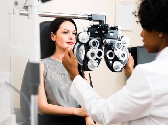 Optometrist examining a young woman's vision during LASIK eye surgery consultation 