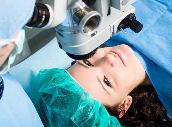 Woman covered with sterile drapes smiling after successful Lasik eye surgery