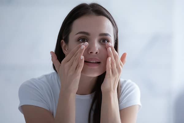 Woman looking at a mirror to take care of her eyes after EVO Visian ICL treatment